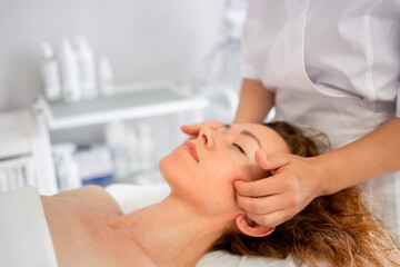 Obraz na płótnie Canvas Massage therapist massaging woman face and body