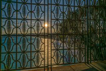 Coucher de soleil sur la promenade des anglais de Nice sur la C&ocirc;te d'Azur au travers de grilles