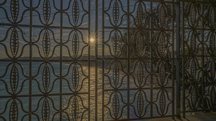 Coucher de soleil sur la promenade des anglais de Nice sur la Côte d'Azur au travers de grilles