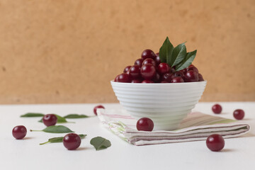 Cherry berries in a white cup on the table on a light background, modern rustic style