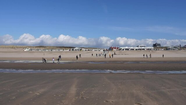 people walk and spend their free time on the beach in windy weather. The Netherlands. The beach with sea foam on a windy day. The Hague beach