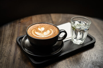 Hot coffee latte with latte art milk foam in cup mug on wood desk on top view. As breakfast In a coffee shop at the cafe,during business work concept,vintage style
