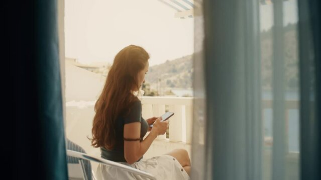 A beautiful woman uses her smartphone on a seaview terrace