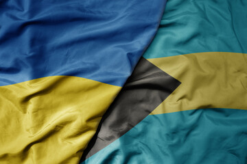 big waving national colorful flag of ukraine and national flag of bahamas .