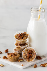A pile of salted caramel pecan fat bombs with a bottle of fresh milk.