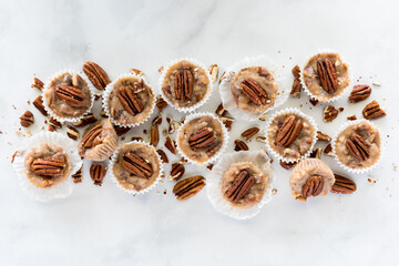 A row of salted caramel pecan fat bombs with chopped pecans scattered around.