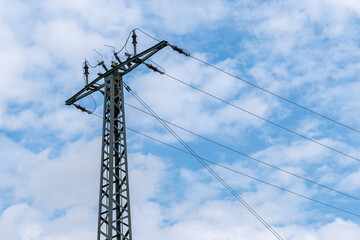 Obraz premium A mast of high-voltage wires against a blue sky with light clouds