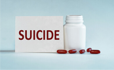 Suicide - word on card near bottle with pills