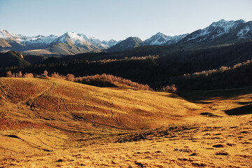 Autumn landscape of the nature of the mountains on a trip with snow-capped winter peaks in the background, off roads