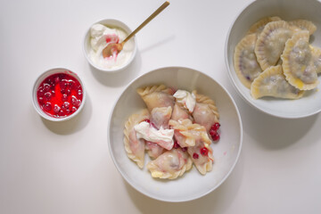Ukrainian varenyki on a white table in a bowl with sauces nearby. delicious homemade Ukrainian food