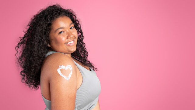 Portrait Of Happy Black Plus Size Woman With Body Lotion In Heart Shape On Shoulder, Panorama, Free Space