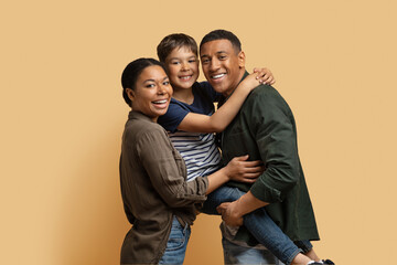 Portrait of cute black family posing together on colored background