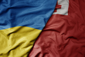 Fototapeta premium big waving national colorful flag of ukraine and national flag of Tonga .