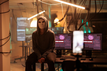 Young hacker with anonymous mask attacking computer server, committing cybercrime. Database system...