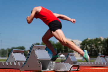 un strating-block posé sur une piste d'athlétisme avec un athlète au départ