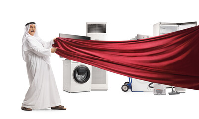 Arab man in traditional clothes pulling a red piece of cloth in front of electrical appliances - obrazy, fototapety, plakaty