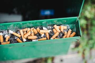 Public green ashtray with burned cigarettes, Cigarette butts in public ashtray 