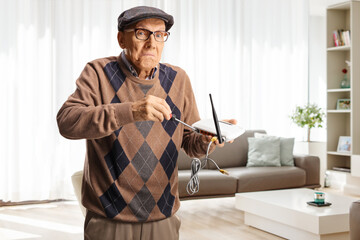 Funny old man fixing a router with a screwdriver at home