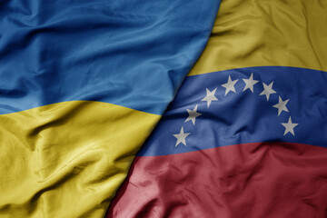 Fototapeta premium big waving national colorful flag of ukraine and national flag of venezuela .
