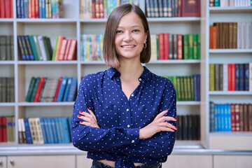 Portrait of confident female college student inside library in educational building