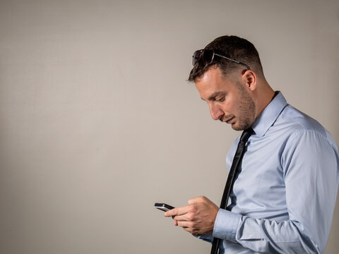 Hombre elegante mirando su celular con mala postura en su espalda