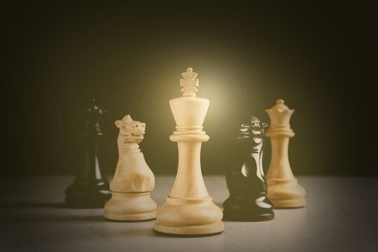 Different chess pieces on grey table against dark background