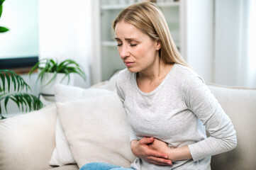 Woman holding her stomach suffering from strong pain