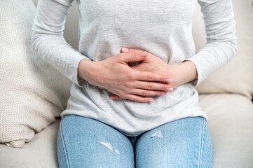 Close-up view of woman touching abdomen and feeling discomfort