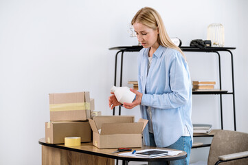 Female warehouse worker packing fragile ceramic vase in cardboard box