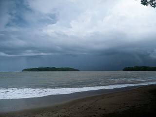 Moody weather with dark storm clouds over tropical beach during rainy season