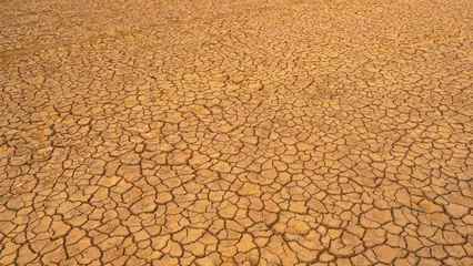 Gordijnen AERIAL: Pattern of cracks on a desolate desert landscape due to lack of rain © helivideo