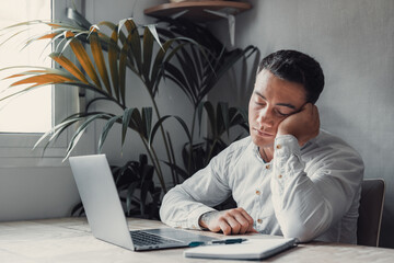 Exhausted young Caucasian male employee sleep desk at office overwork preparing report. Tired male fall asleep doze off at workplace, work late to meet deadline. Fatigue, exhaustion concept..
