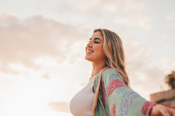 Portrait of one young woman at the beach with openened arms enjoying free time and freedom outdoors. Having fun relaxing and living happy moments..