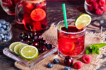 Refreshing berry cocktail with ice and lemon. Raspberry, lime, strawberry, blueberry, and leaves mint. Berry mojito close-up.