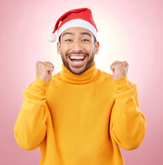 Portrait, excited and smile, man with Christmas hat for fun and yes at festive holiday on pink...