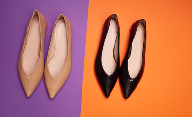 Two pairs of stylish women's pointed-toe shoes of different colors but the same model on a bright two-colored background. Top view, flat lay. The concept of modern stylish footwear