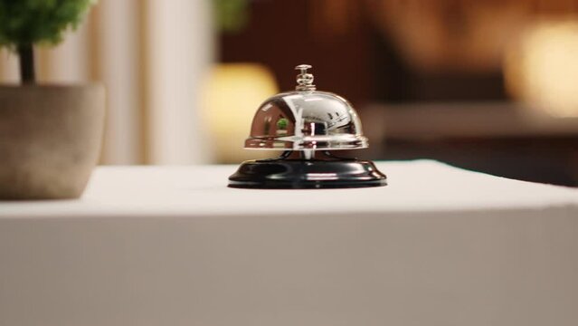Extreme close up of concierge bell next to mini plant on cozy hotel lounge check in desk. Elegant service bell on modern stylish hospitality industry resort reception counter