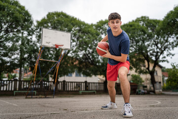 Obraz premium One caucasian teenager stand on basketball court with ball