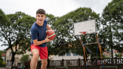One caucasian teenager stand on basketball court with ball