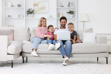 Happy family with laptop spending time together on sofa at home
