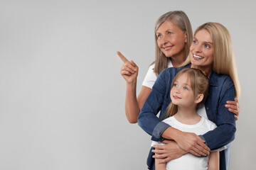 Three generations. Happy grandmother, her daughter and granddaughter on light gray background, space for text