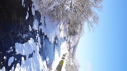 4K Landscape of Beautiful nature in winter season. Small town canal covered in snow with forest mountain background. Local village in Japan in snow day. Season change concept. - Powered by Adobe