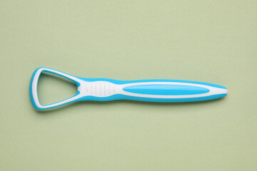Light blue tongue cleaner on olive background, top view