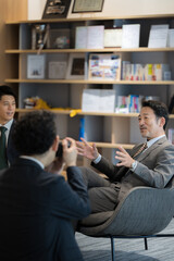 笑顔でインタビューなどを受ける社長や教授のイメージ　カメラマンの前ボケあり　縦