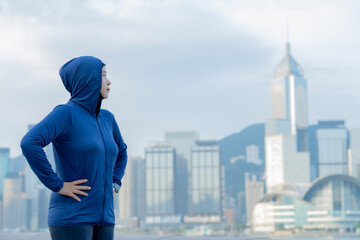 Glad smiling young asian muslim woman in hijab with fitness tracker running on building background outdoor. Fitness outside, jogging in morning, body and health care, training, concept muslim sport.