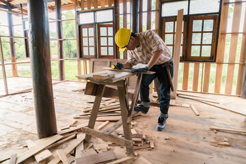 Carpenter working on his desk in construction design Wear a hat and goggles