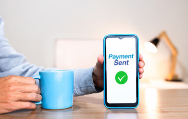 Hand holding a smartphone with the screen showing confirmation of payment sent through an instant payment system.
