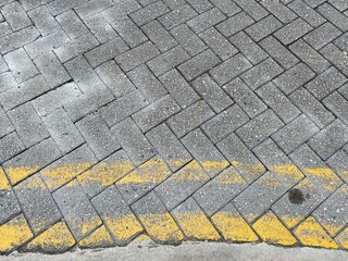 Faint double yellow lines on grey road bricks.