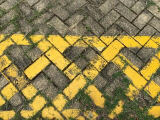 Yellow no parking lines on grey road bricks.