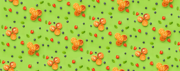Many cottage cheese pancakes and berries on green background. Pattern for design